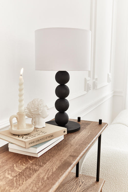 Table lamp with a white shade and black cylindrical base on a light gray background