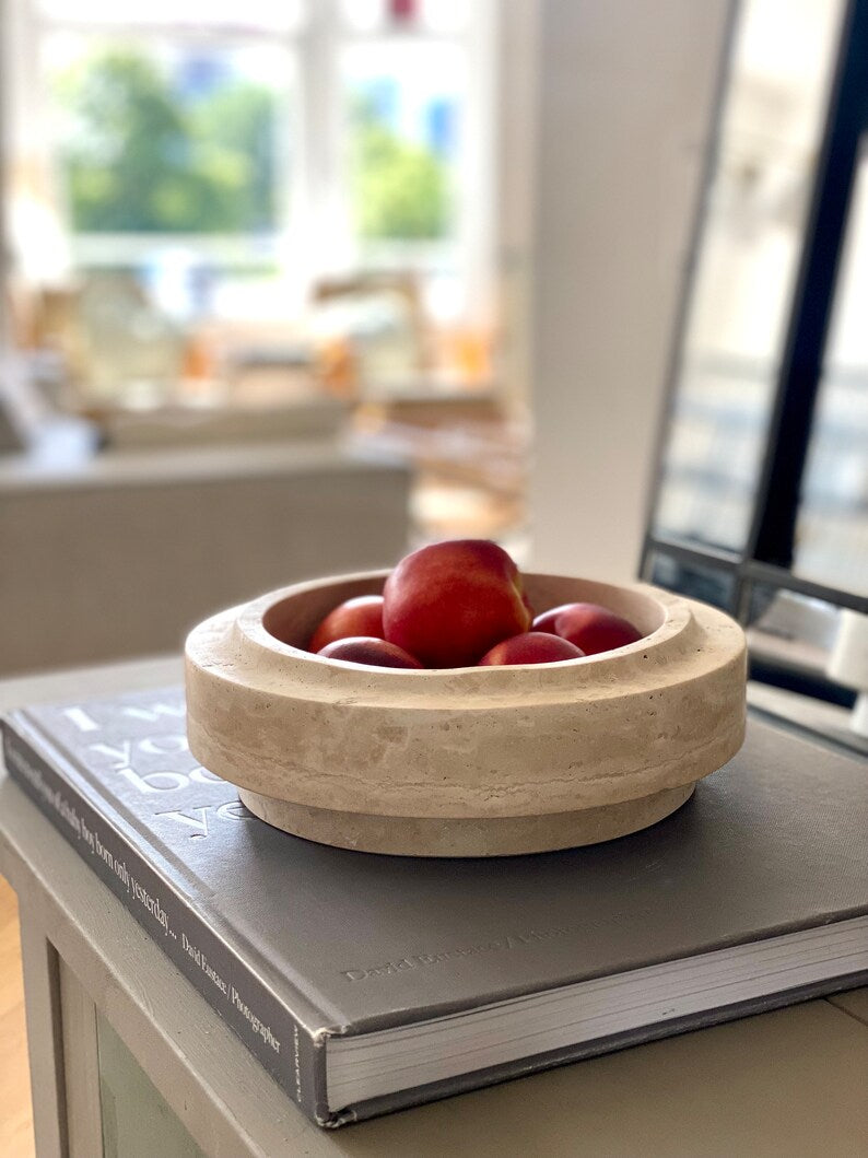 Wooden bowl with fruits on a book in a kitchen setting