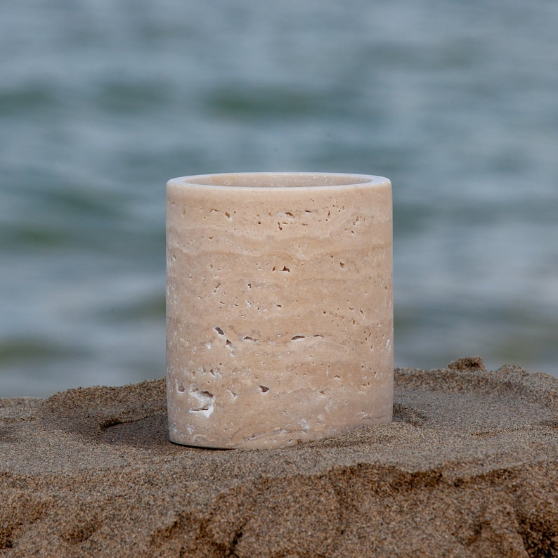 Beige ceramic toothbrush holder with two bamboo toothbrushes on a light gray background