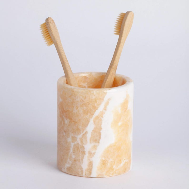 Marble-patterned toothbrush holder with bamboo toothbrushes on a light gray background