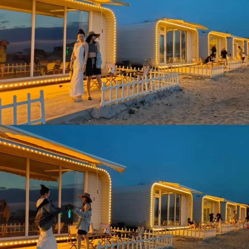 A two-panel photo shows a beachside modern white building with warm yellow string lights around the windows and porch, with several people standing outside at dusk. The top panel has two women conversing on the porch, and the bottom panel shows a man and a woman taking a photo together.