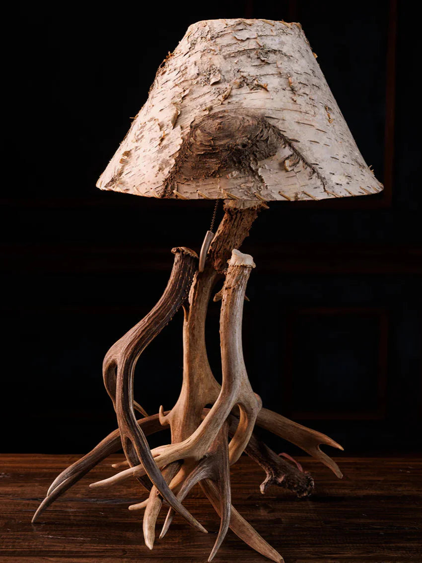 Table lamp with deer antlers and a natural wood shade on a dark background