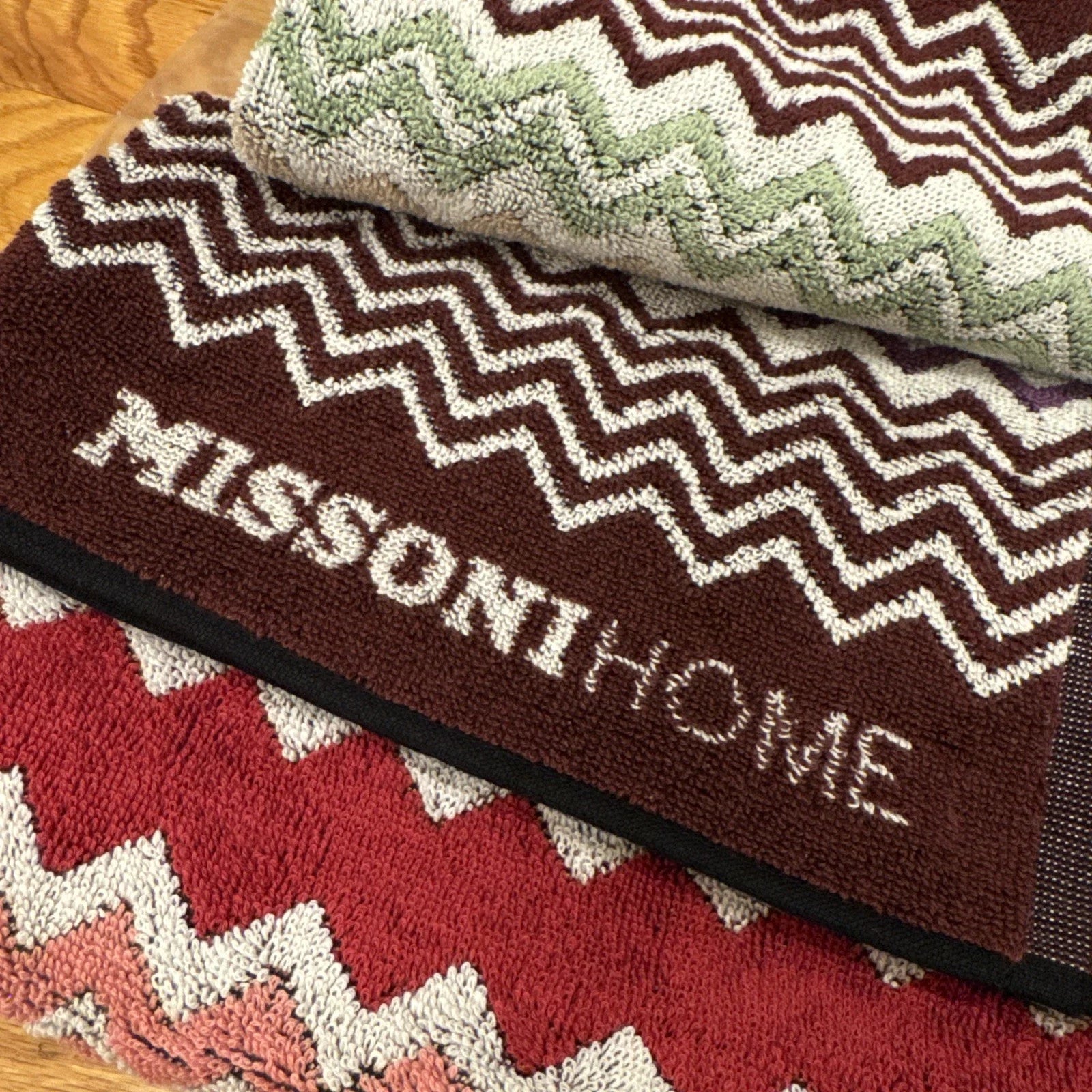 Multicolored zigzag patterned throw blanket with 'Missoni Home' branding on a wooden floor.