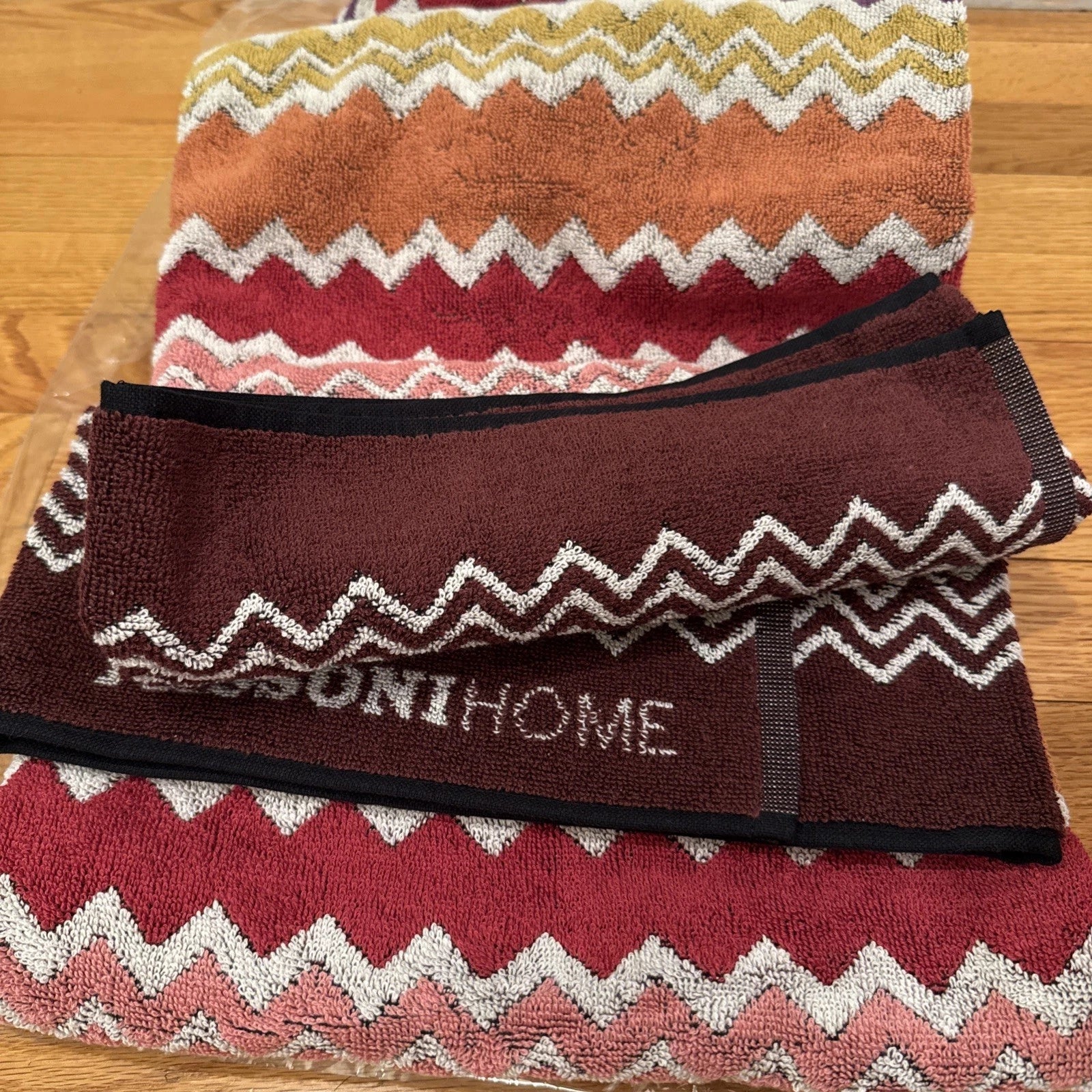 Multicolored zigzag patterned throw blanket with 'Missoni Home' branding on a wooden floor.